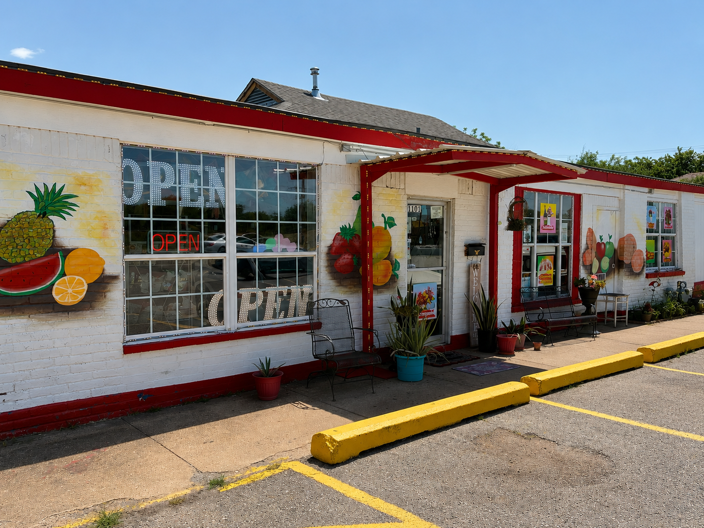 Fachada de Angie's Frutería con letrero OPEN, murales de frutas y entrada con plantas.